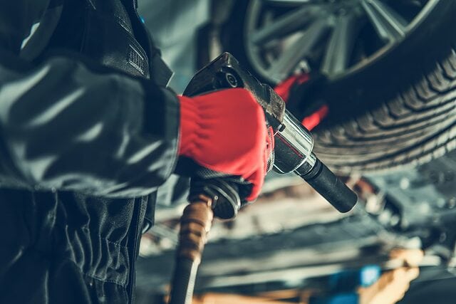 Mechanic with impact wrench changing tire